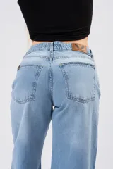 Pantalón wide leg de tiro medio-bajo, con corte holgado y pernera ancha. Presenta un diseño clásico de cinco bolsillos con cierre de botón y cremallera, en un tono azul claro con acabado lavado.