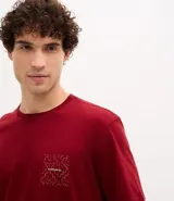 Remera de corte comfort color bordó, con cuello redondo y manga corta. Presenta una pequeña estampa gráfica de follaje con lettering en el lado izquierdo del pecho.