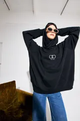 Canguro negro oversize de algodón con capucha y bolsillo delantero tipo canguro. Logo bordado en el pecho.