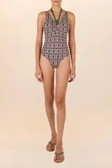 Traje de baño entero verde oscuro con estampado geométrico de círculos en rosa y blanco. Tiene escote en V, breteles halter verdes y aro circular central.
