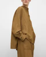 Camisa de efecto arrugado color tostado, con cuello mao, cierre frontal de botones, manga larga y bolsillo de plastrón en el pecho.