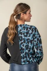 Buzo de manga larga con cuello redondo, combinado en dos tonos: negro liso en la mitad derecha y estampado animal print blanco y negro en la mitad izquierda.
