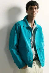Cazadora relaxed fit de denim de algodón color turquesa, con cuello solapa, manga larga con puño abotonado, bolsillos frontales con solapa y cierre de botones metálicos.