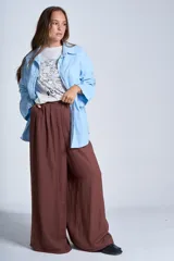 Sobrecamisa color beige confeccionada en gabardina, de corte holgado, con cuello camisero, cierre frontal con botones, dos bolsillos de parche en el pecho y mangas largas con puños abotonados.