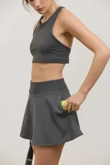 Top deportivo de sujeción media con escote redondo y espalda abierta. Presenta un diseño al cuerpo con elástico oculto en la cintura.