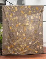 Mantel rectangular de lino color marrón con estampado de hojas y flores en tonos dorados y blancos.