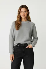 Sweater de algodón gris, holgado, con cuello a la base y mangas largas.