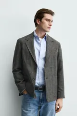 Blazer de corte regular confeccionado en tejido con lana, con cuello de solapas de muesca, cierre frontal de dos botones, mangas largas con puños abotonados y bolsillos de plastrón en la parte frontal.