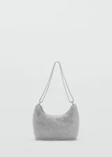 Bolso de mano tipo baguette con diseño estructurado, recubierto completamente por cristales facetados sobre una base de aluminio. Cuenta con doble asa de cadena metálica, cierre superior de cremallera y forro interior de poliéster.