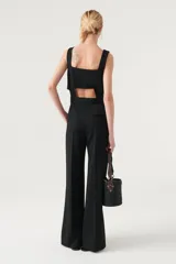 Mono negro con corte a la cintura y pantalón palazzo. Presenta breteles anchos y aberturas laterales con botones a presión.