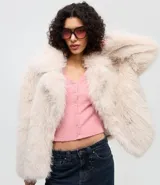 Cardigan de punto texturizado color rosado, con escote en V, cierre frontal por botones, mangas largas y acabado con volados sutiles en el ruedo y los puños.