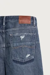 Jeans flare fit de denim azul oscuro con roturas y costuras decorativas en las perneras. Tiro medio y diseño de cinco bolsillos.