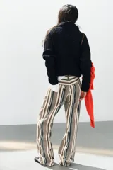 Jeans de tiro medio con diseño de rayas verticales en tonos beige, marrón y verde, corte boyfriend, cinco bolsillos y cierre frontal con cremallera y botón.