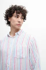 Camisa de manga larga con cuello abotonado y bolsillo en el pecho. Diseño a rayas verticales en tonos rosa, celeste y beige sobre fondo blanco.