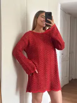 Vestido corto de tejido calado con patrón de ondas, confeccionado en algodón y lurex. Presenta mangas largas, cuello redondo y diseño holgado.