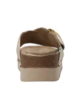 Sandalia de plataforma baja Halifax con tiras cruzadas de cuero sintético en color dorado, suela de corcho y base dentada. Incluye una hebilla metálica circular decorativa en el lateral.