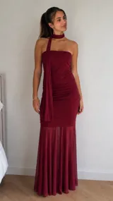 Vestido largo bordó con diseño strapless, cuerpo drapeado y falda larga semitransparente con vuelo. Incluye una tira envolvente para el cuello estilo choker.