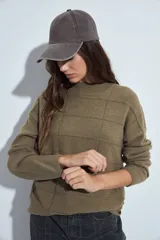 Sweater de punto gris con cuello a la base y diseño de trama geométrica en relieve. Presenta un calce relajado con mangas largas y puños tejidos.