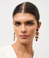 Caravanas medianas con diseño alargado, compuestas por múltiples piezas en forma de gota y óvalos de resina en tonos marrones, crema y blanco, engarzadas en metal dorado.