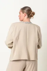 Chaqueta negra de crepe con solapas y borde frontal con lentejuelas. Corte recto y mangas largas.