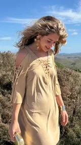 Vestido corto color beige, con escote en V con cordones, mangas 3/4 acampanadas con cordones, hombros descubiertos y corte holgado.