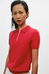 Top de punto de algodón color rojo, con cuello polo, manga corta y cierre frontal con cremallera blanca a contraste.