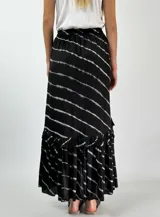 Pollera larga de color negro con estampado de rayas horizontales blancas difuminadas y volados en el ruedo.