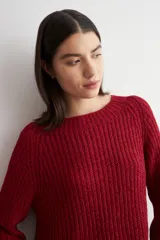 Sweater de punto con textura jaspeada en tonos marrones, de corte recto, cuello redondo y mangas largas. Presenta un diseño con ruedo curvo.