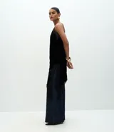 Vestido corto de terciopelo negro, estilo slip dress, con escote corazón, breteles finos y detalles de encaje en el escote y en el ruedo asimétrico con terminación en punta lateral.