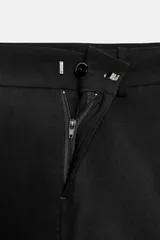 Falda pantalón negra de tiro medio con cierre frontal y hebilla metálica. Presenta bolsillos delanteros y falsos bolsillos de vivo en la espalda.