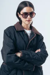 Campera acolchada de diseño matelasse con pespuntes ondulados, cuello clásico en contraste y cierre frontal con botones. Presenta bolsillos frontales con ribetes a tono y calce relajado.
