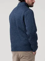 Polar de tejido jaspeado azul marino con cuello alto y cierre frontal parcial con tirador de cuero. Presenta bolsillos laterales con cierre.