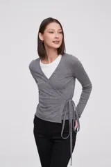 Saco tipo cardigan cruzado de punto, color gris melange, con escote en V profundo, mangas largas y lazo lateral para ajustar a la cintura.