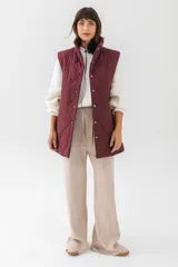 Chaleco acolchado de corte recto y largo medio, con diseño de rombos, cuello alto y cierre frontal con botones a presión.