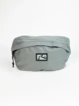Riñonera gris de la marca Rusty, confeccionada en tela resistente, con cierre principal y parche frontal con el logo de la marca.