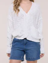 Cardigan blanco de punto liviano y texturado, de corte holgado y diseño casual. Cuenta con escote en V pronunciado, abotonadura frontal, mangas largas con hombros caídos y bolsillos delanteros tipo parche.