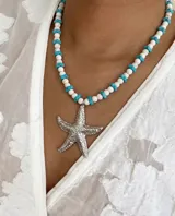 Collar de piedras naturales blancas y discos turquesas, con dije de estrella de mar texturizado en acero.