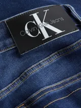 Jeans de hombre Calvin Klein de corte slim, color azul oscuro con efecto desgastado y lavado en la parte frontal de los muslos. Presenta cinco bolsillos y cierre de cremallera.