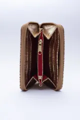Billetera marrón tipo sobre con cierre de cremallera, confeccionada en cuero con textura tipo cocodrilo y forro textil rojo. Cuenta con múltiples ranuras para tarjetas, documentos y billetes.