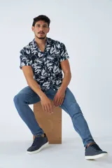 Camisa de manga corta con estampado botánico de hojas en tonos azul y blanco. Presenta cuello clásico, cierre frontal abotonado y corte slim.