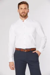 Camisa blanca lisa de manga larga con bolsillo en el pecho. Cuello con botones, tablón central en la espalda, botones personalizados y logo bordado en el bolsillo.