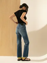 Pantalón de jean de tiro alto, corte recto, color azul medio con lavado parejo y un corte en la rodilla.