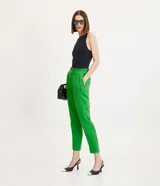 Pantalón zanahoria de vestir color verde, con cintura alta, bolsillos laterales con detalle de botones y corte sastrero.