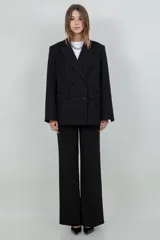 Blazer oversize negro con un sutil brillo, solapas de muesca, doble botonadura frontal y bolsillos con solapa.