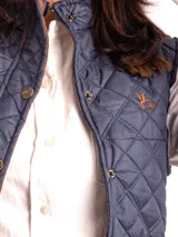 Chaleco capitoneado color rosa claro, con cuello alto, cierre frontal con botones a presión y logo bordado en el pecho.