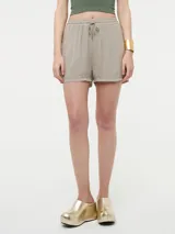 Short color beige con rayas verticales brillantes, pretina elástica ajustable con cordón y bolsillos laterales.