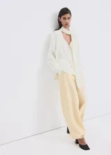 Blusa de modal y poliéster color blanco marfil, con diseño recto, escote en V, mangas largas y detalle de fular incorporado en el cuello. Cierre frontal con botones.