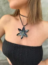 Collar con dije en forma de flor pintado a mano con detalles de difuminado y mostacillas en relieve. El dije cuelga de un tiento sintético regulable.