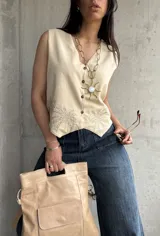 Chaleco color crema de lino liviano con bordado de palmeras en la terminación y corte recto.