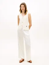 Chaleco slim de punto de puro algodón peinado, color blanco, con cuello en V, cierre frontal de botones dorados y logo bordado en la parte inferior.